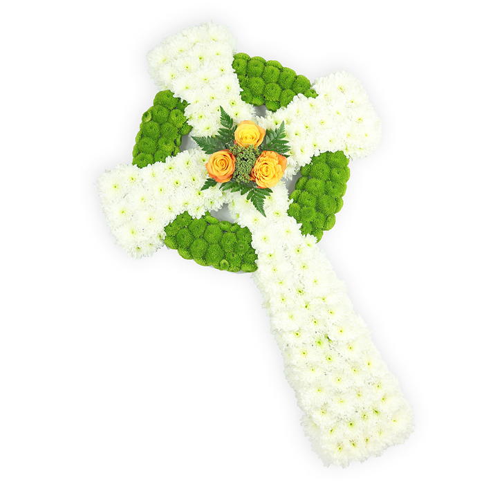 This photograph shows an expertly made floral Celtic cross presented on a pristine white surface and viewed from a subtle overhead perspective that highlights its three-dimensional shape. The structural backbone of the cross is densely packed white spray chrysanthemums, their close-set petals forming a plush, serene canvas across the arms and stem. Bright, almost lime-green button chrysanthemums are strategically placed to define the circular boss at the centre and to punctuate alternating zones along the horizontal arms, resulting in a rhythmic interplay of colour that echoes traditional Celtic patterns. Anchoring the design at the intersection is a compact cluster of three warm orange-yellow roses; their petals open toward the viewer like a small, glowing sun and are gently cradled by darker green foliage, creating depth and a calming contrast. The soft studio lighting brings out the tactile differences between the chrysanthemums' matte clusters and the satin sheen of the roses without overpowering the overall restraint of the piece. The palette-white, green, and orange-hints at Irish heritage and can be particularly meaningful for memorials or funerals of those with Celtic roots, or for commemorations held at local chapels near the Thames, the embankment or the churches around Millbank and Pimlico. A creation like this reads as a measured expression of grief and honour: meticulous in its geometry, tender in its colour, and meant to comfort while conveying a sense of enduring respect.